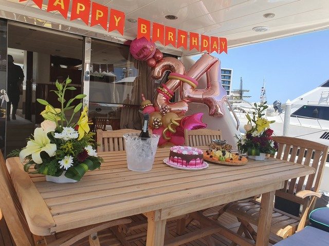Birthday table with flowers, balloons and cake set up on a yacht