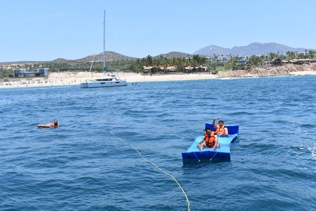 Guests relaxing on a floating water mat during a swim stop